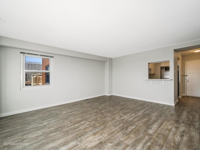 unfurnished living room with baseboards and wood finished floors