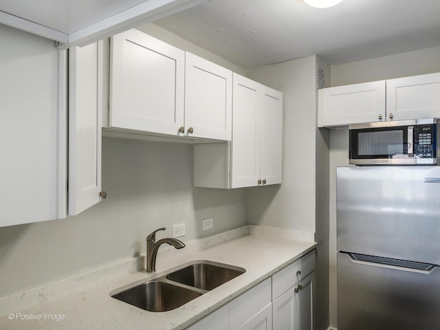 kitchen with a sink, stainless steel appliances, and white cabinetry