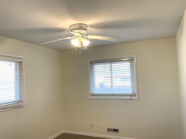spare room with visible vents, baseboards, ceiling fan, and dark carpet