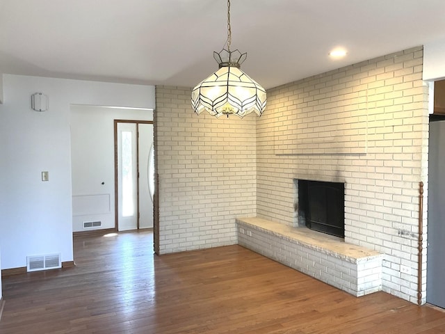 unfurnished living room with visible vents, wood finished floors, and a fireplace