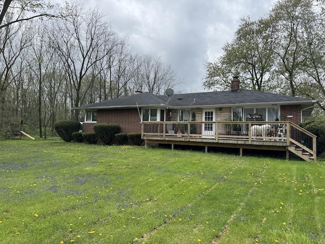 rear view of property featuring a lawn, brick siding, a wooden deck, and a chimney