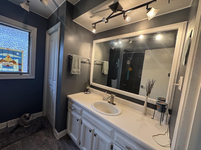 bathroom featuring vanity, baseboards, wood finished floors, and a stall shower