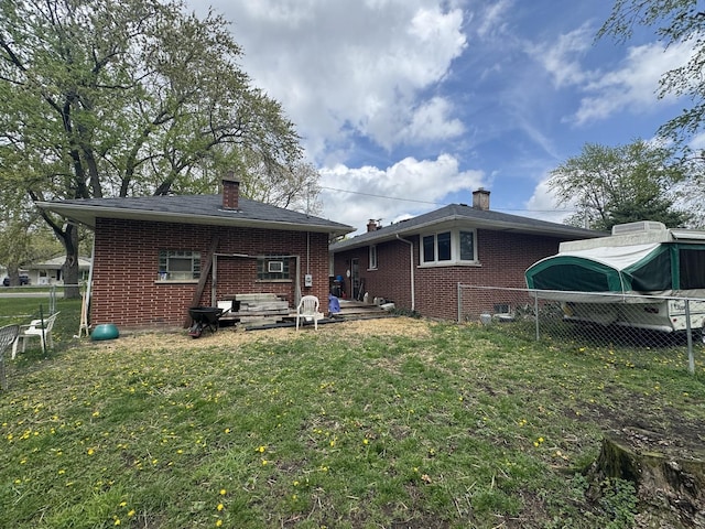 rear view of property featuring a lawn, brick siding, and fence