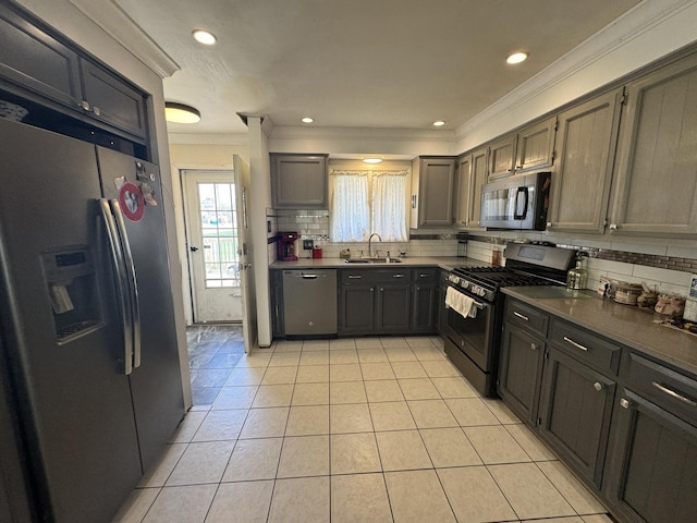 kitchen with ornamental molding, tasteful backsplash, a sink, light tile patterned floors, and stainless steel appliances