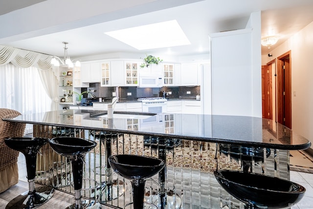 14650 Lamon Ave, Midlothian, IL 60445 - kitchen featuring decorative backsplash, white appliances, a kitchen breakfast bar, white cabinets, and a sink