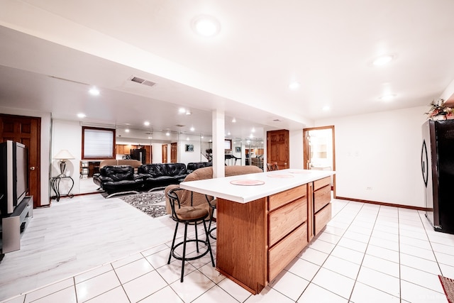 14650 Lamon Ave, Midlothian, IL 60445 - kitchen with a kitchen breakfast bar, a center island, light countertops, freestanding refrigerator, and light tile patterned flooring