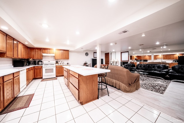 14650 Lamon Ave, Midlothian, IL 60445 - kitchen with visible vents, white appliances, open floor plan, a kitchen bar, and light countertops