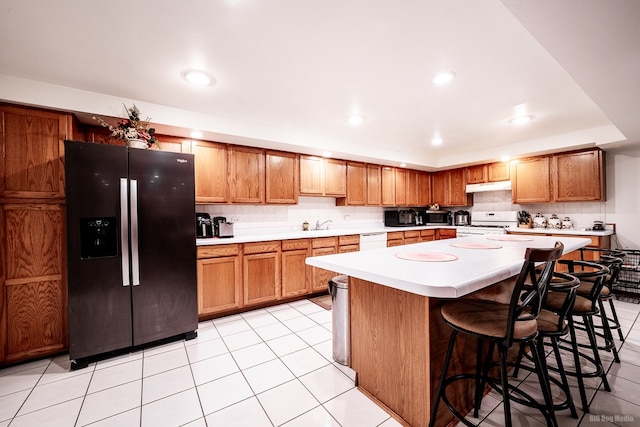 14650 Lamon Ave, Midlothian, IL 60445 - kitchen with brown cabinetry, light countertops, a kitchen breakfast bar, and white appliances