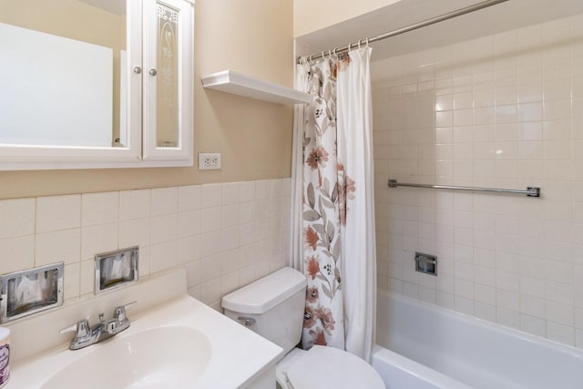 bathroom with tile walls, shower / bathtub combination with curtain, vanity, and toilet