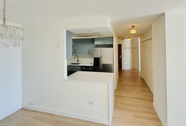 kitchen with stainless steel fridge with ice dispenser, a sink, light countertops, light wood-type flooring, and a chandelier