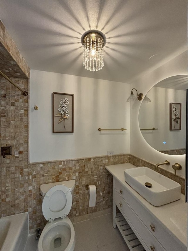 bathroom with tile walls, toilet, a wainscoted wall, vanity, and tile patterned floors