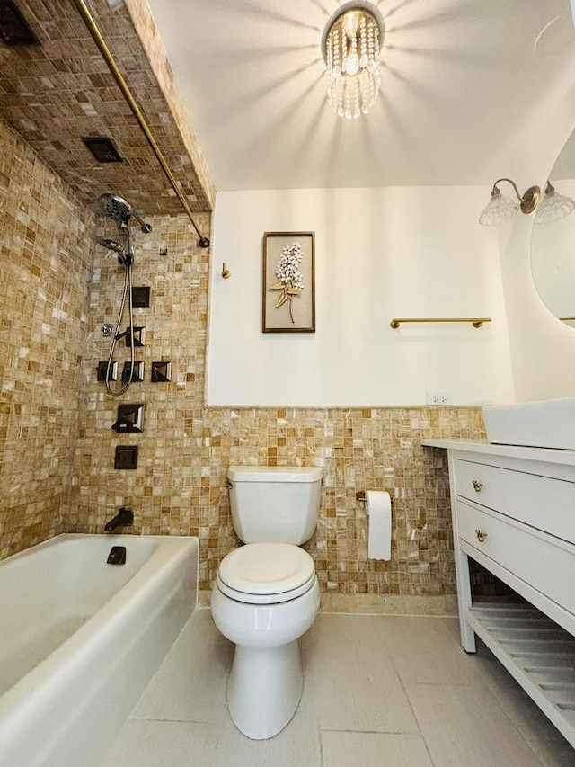 bathroom with toilet, vanity, tub / shower combination, tile walls, and wainscoting