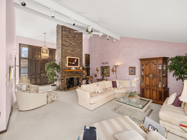 living room featuring a fireplace, rail lighting, carpet, and ceiling fan with notable chandelier