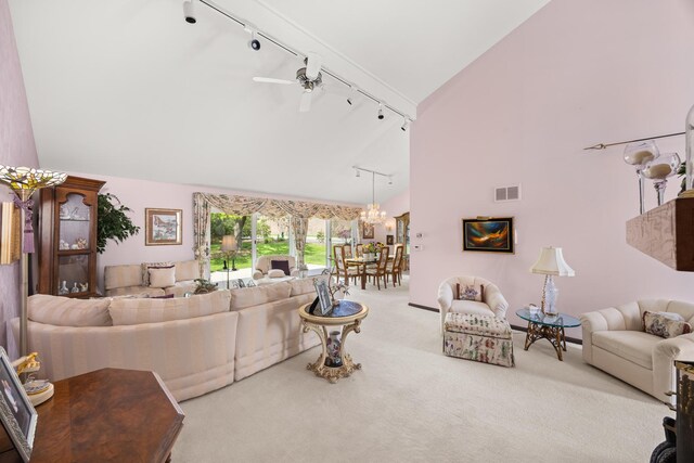 living room with carpet flooring, ceiling fan with notable chandelier, high vaulted ceiling, rail lighting, and visible vents