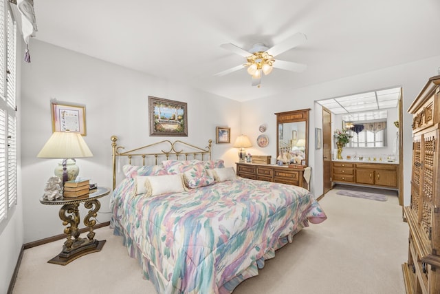 bedroom with light colored carpet, ensuite bath, baseboards, and ceiling fan