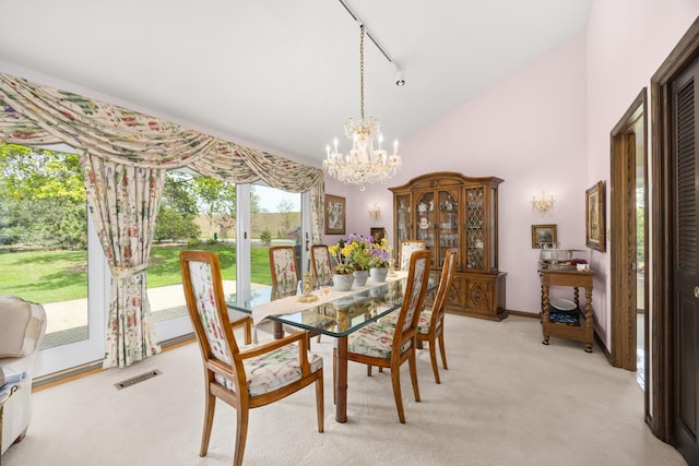 dining area featuring light colored carpet, high vaulted ceiling, track lighting, visible vents, and a notable chandelier