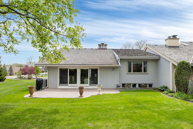 back of property with a patio area, a chimney, and a lawn