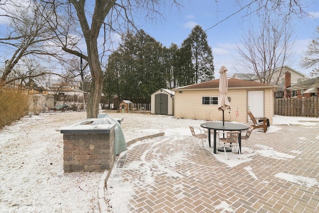 exterior space featuring an outdoor structure, fence, outdoor dining area, and a storage unit