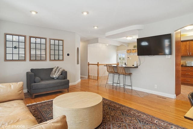 living room with visible vents, wood finished floors, baseboards, recessed lighting, and arched walkways