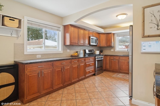 kitchen with appliances with stainless steel finishes, backsplash, and brown cabinets