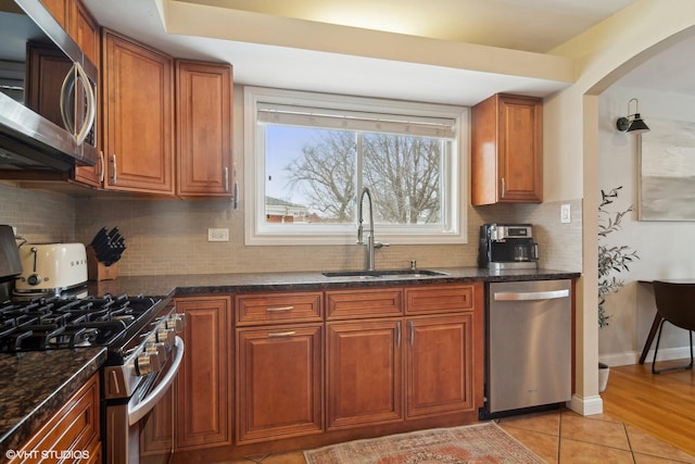 kitchen with a sink, decorative backsplash, brown cabinets, and stainless steel appliances