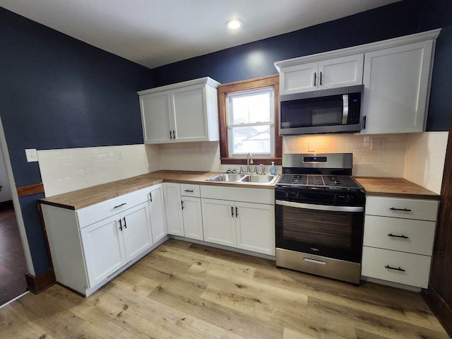 257 S Alma Ave, Kankakee, IL 60901 - kitchen featuring butcher block countertops, light wood-type flooring, white cabinetry, a sink, and stainless steel appliances