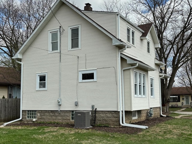257 S Alma Ave, Kankakee, IL 60901 - view of property exterior featuring fence, a chimney, a lawn, and central AC