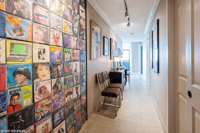 corridor featuring crown molding, baseboards, tile patterned flooring, and rail lighting