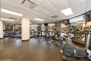 workout area featuring decorative columns, a drop ceiling, and visible vents