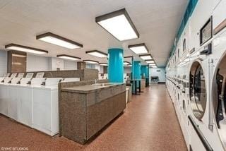 community laundry room with stacked washer and dryer, washing machine and dryer, and a sink
