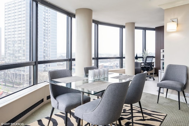 dining area with light colored carpet, a wealth of natural light, and expansive windows