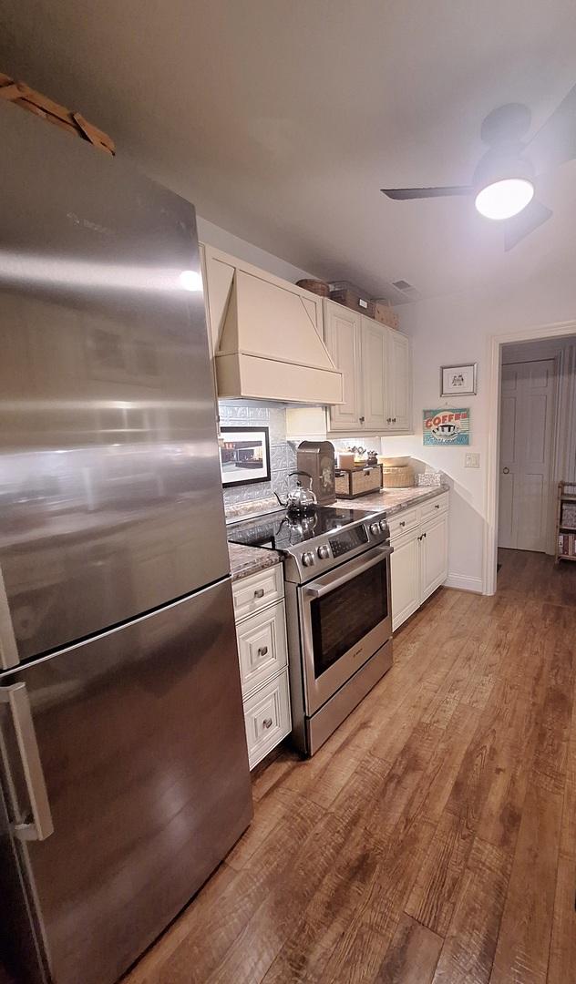 7323 Heritage Ct Unit 1D, Frankfort, IL 60423 - kitchen featuring appliances with stainless steel finishes, wall chimney range hood, white cabinets, and wood finished floors