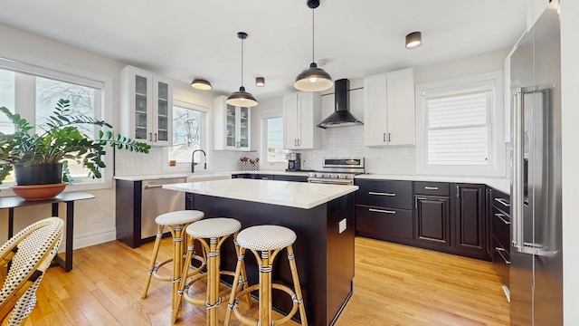 5650 W Grace St, Chicago, IL 60634 - kitchen featuring a healthy amount of sunlight, a center island, stainless steel appliances, and wall chimney exhaust hood