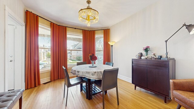 5650 W Grace St, Chicago, IL 60634 - dining room featuring baseboards, light wood-style flooring, and a chandelier