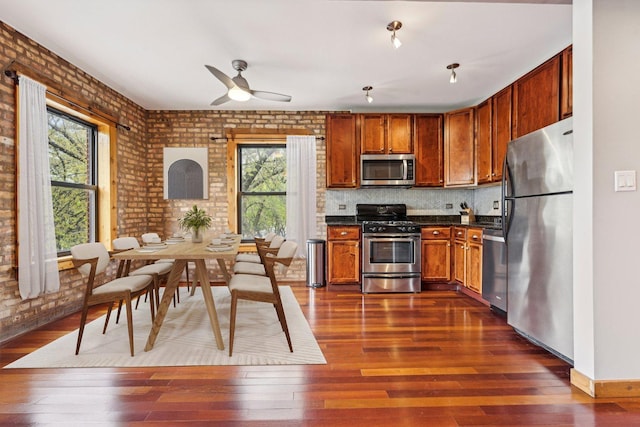 1247 W Roscoe St Unit 2, Chicago, IL 60657 - kitchen featuring appliances with stainless steel finishes, dark countertops, dark wood-style floors, a ceiling fan, and brick wall