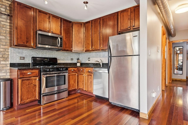 1247 W Roscoe St Unit 2, Chicago, IL 60657 - kitchen featuring stainless steel appliances, dark wood-style flooring, decorative backsplash, dark stone countertops, and a sink