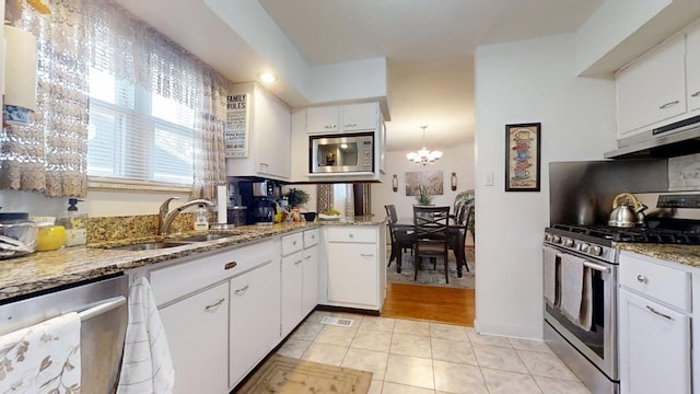 1309 Eureka St, Urbana, IL 61801 - kitchen featuring stainless steel appliances, under cabinet range hood, a sink, light tile patterned floors, and white cabinetry