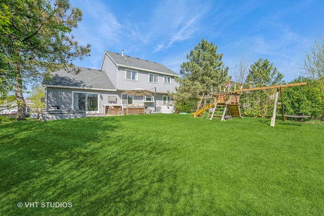 rear view of property featuring a playground, a lawn, and roof with shingles