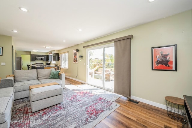 living room with baseboards, light wood-type flooring, and recessed lighting