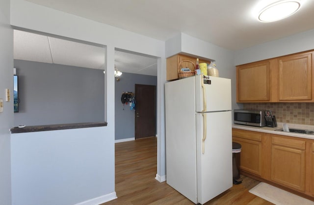 7310 Tiffany Dr Unit 2B, Orland Park, IL 60462 - kitchen featuring light wood-style flooring, freestanding refrigerator, stainless steel microwave, baseboards, and backsplash