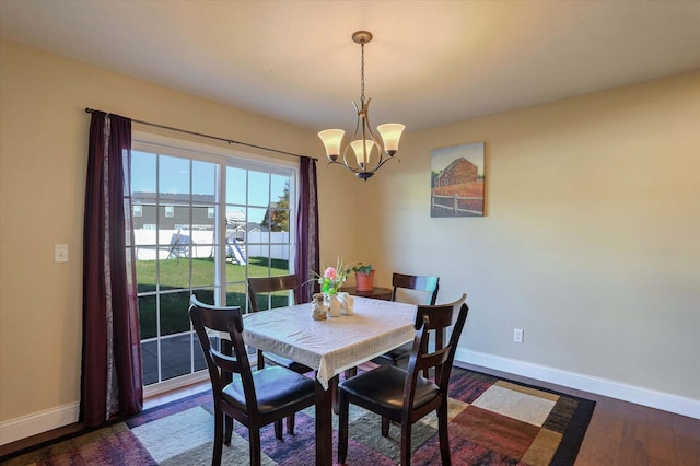 dining area with baseboards, dark wood finished floors, and a chandelier