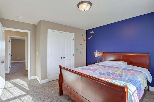 bedroom featuring light colored carpet, a closet, and baseboards