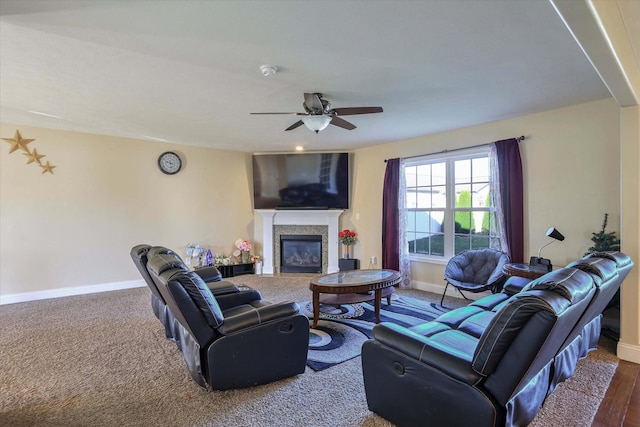 living room featuring baseboards, a ceiling fan, and a glass covered fireplace