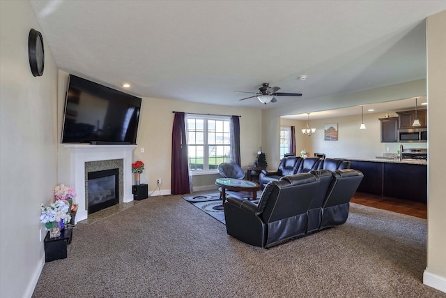 carpeted living room with ceiling fan, baseboards, and a fireplace with flush hearth