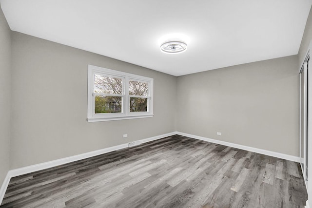 unfurnished bedroom with wood finished floors, baseboards, and a closet