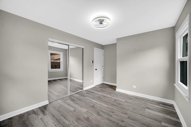 unfurnished bedroom with wood finished floors, baseboards, and a closet