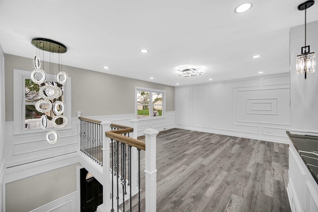 corridor featuring a decorative wall, an upstairs landing, wood finished floors, a wainscoted wall, and recessed lighting