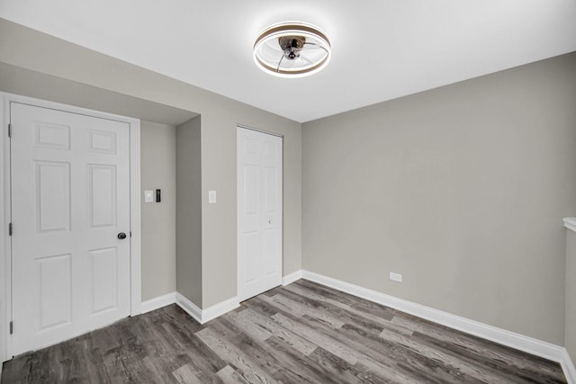 unfurnished bedroom featuring wood finished floors, baseboards, and a closet
