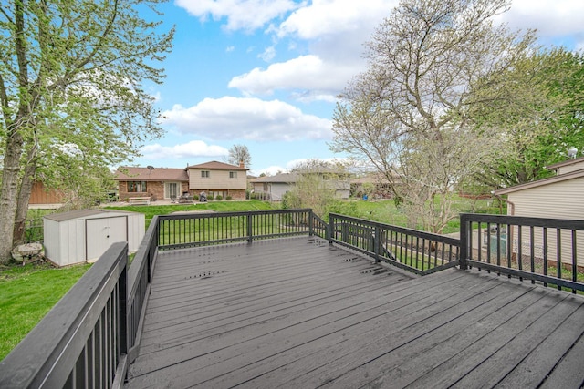 deck featuring a storage shed, a lawn, an outbuilding, and a residential view