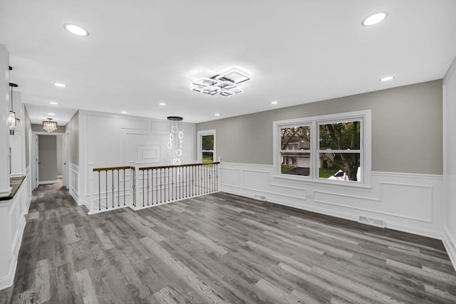 spare room featuring healthy amount of natural light, a wainscoted wall, a decorative wall, recessed lighting, and wood finished floors